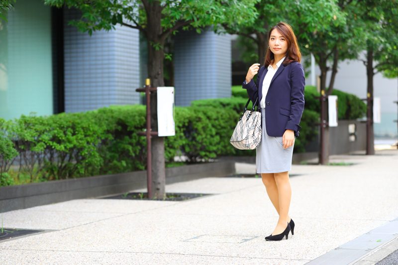 女性らしいシルエットのドレープ入りタイトスカートは紺ジャケットでオフィス仕様に