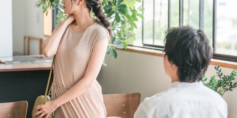 喫茶店にいるカップルの写真。彼女が席を立ち、その場を去ろうとしている