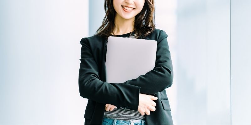 笑顔でパソコンを抱えている若い女性