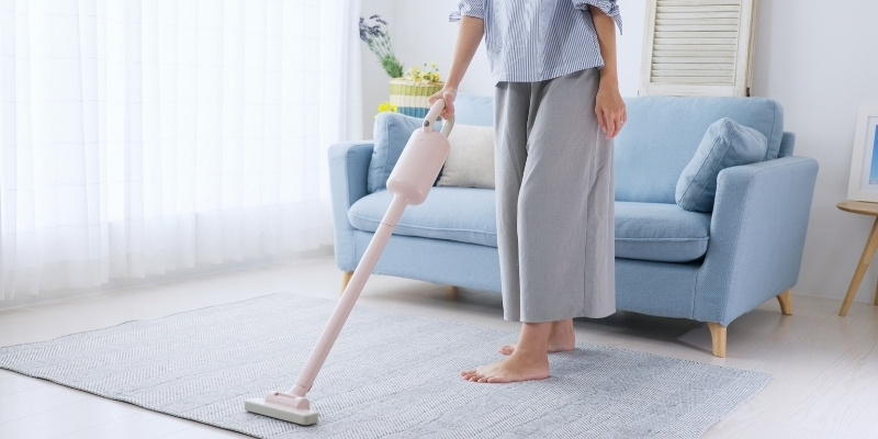 床に掃除機をかけている女性の写真