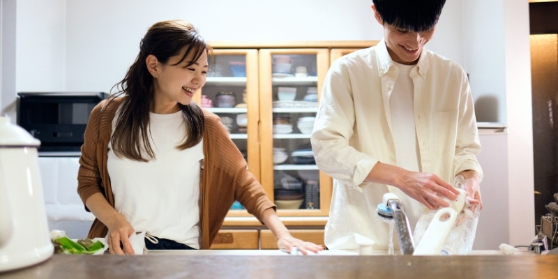食器の後片付けをするカップルの写真