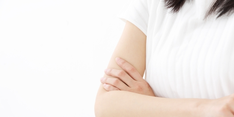 腕を組んで考える女性の写真