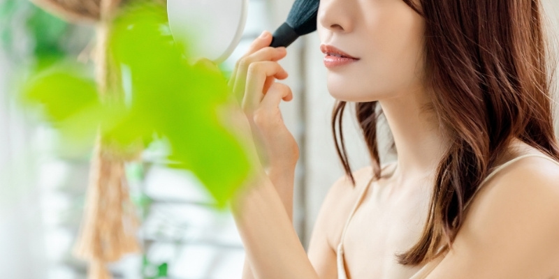 メイクブラシを肌に当てている女性の写真
