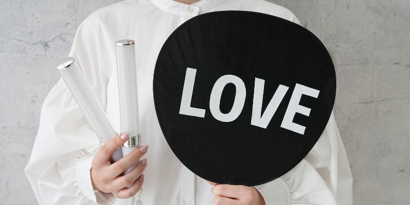 ペンライトとLOVEと書かれたうちわを持った女性の写真
