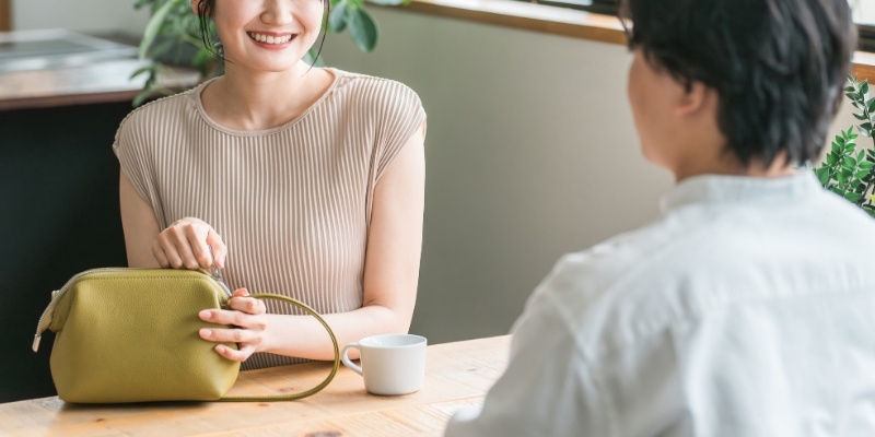 向かい合って座る男性に微笑む女性の写真