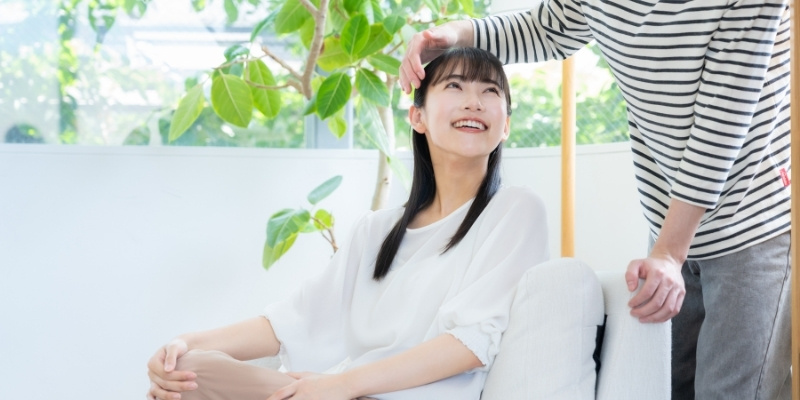 頭をなでられてほほ笑む女性の写真