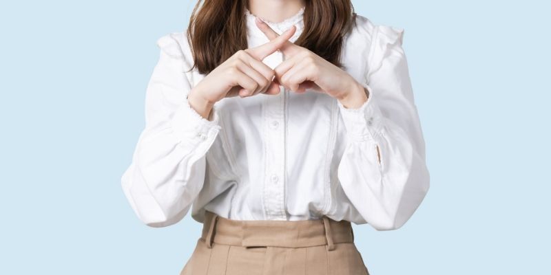 指でバツマークを作る女性の写真
