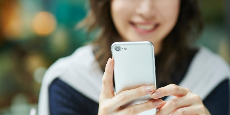 笑顔でスマホを操作する女性の写真