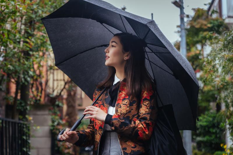 傘をさして街中に佇む女性
