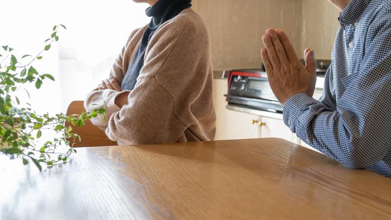 手を合わせている男性と横を向いている女性