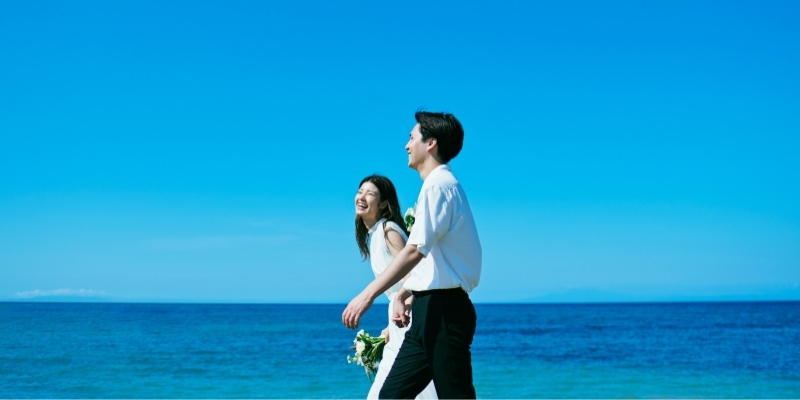 海辺を歩く新郎新婦の写真