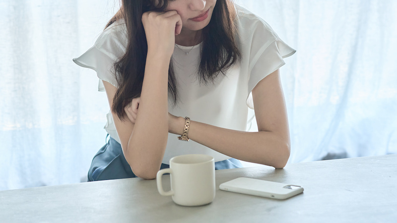 スマホを眺めて悩んでいる様子の人