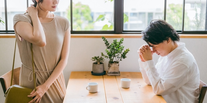 カフェで男性を一瞥して席を立つ女性の写真