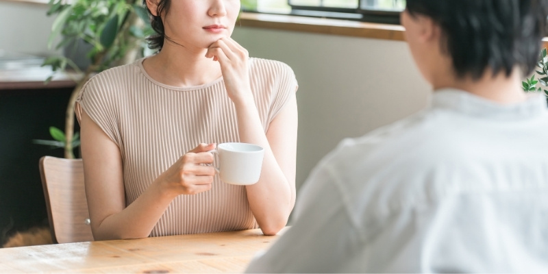カフェで向かいに座っている男性から視線を背ける女性の写真