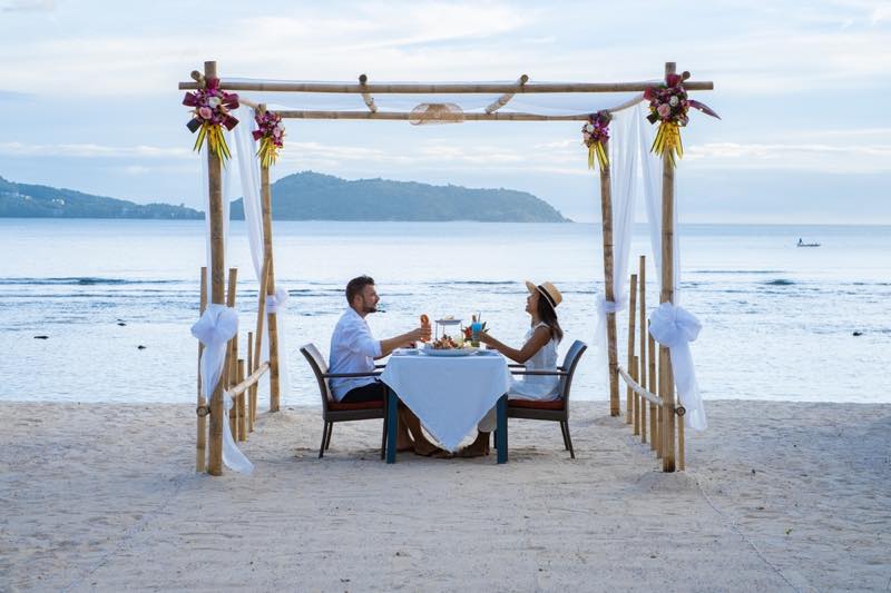 浜辺で結婚式ディナーをする男女