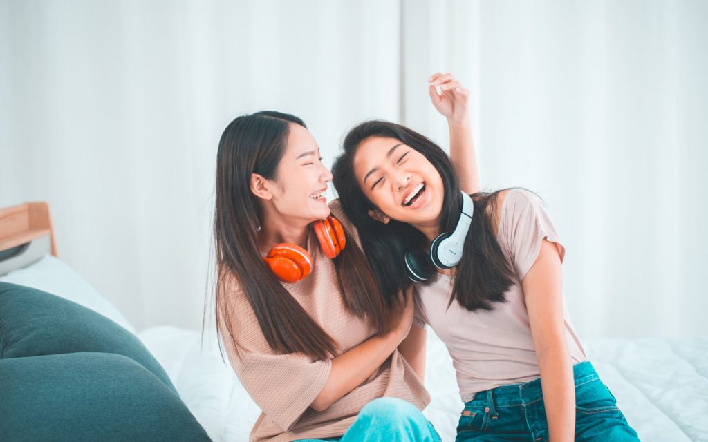 ヘッドホンを首にかけてじゃれる女性たち