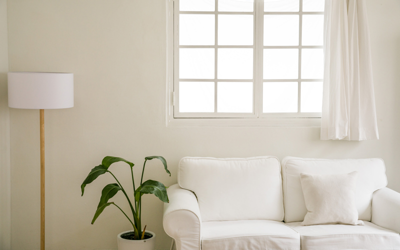 白いソファと白のスタンドライト、窓が置かれている部屋の様子