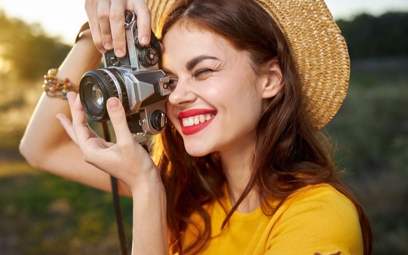 笑顔で趣味の写真を撮る女性