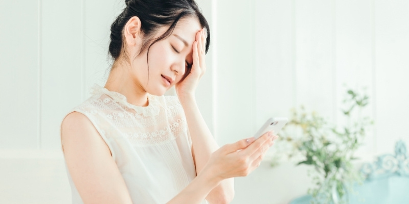 スマホを見て参っている女性の写真