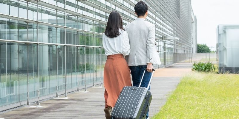 空港でスーツケースを持って歩くカップルの写真