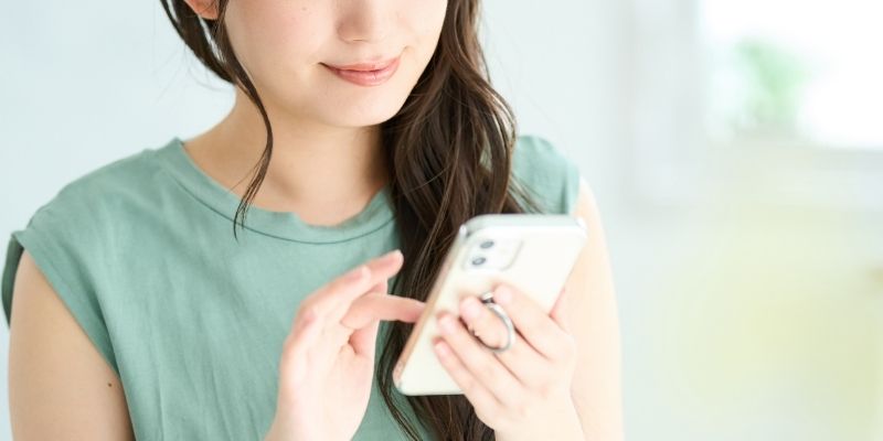 笑顔でスマホを操作する女性の写真
