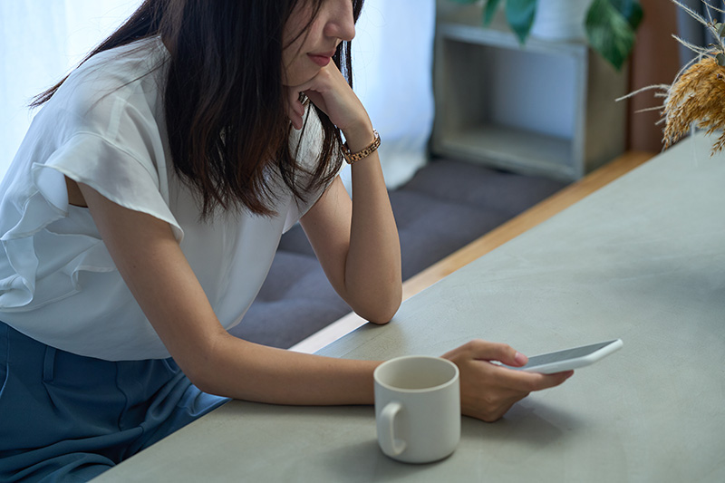 暗い表情でスマートフォンを見つめる女性