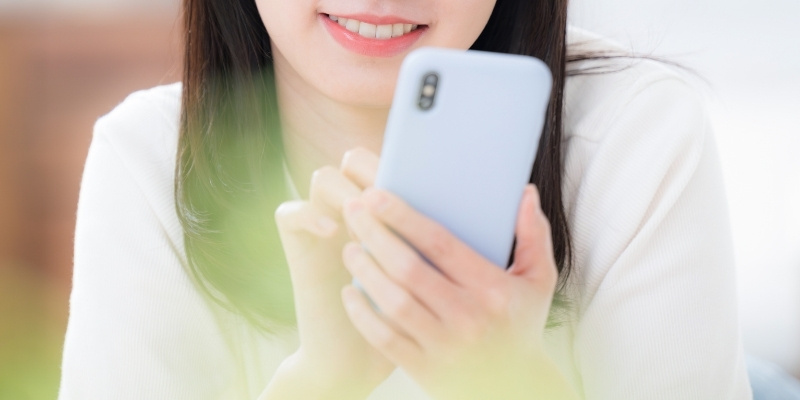 スマホを見てほほ笑む女性の写真