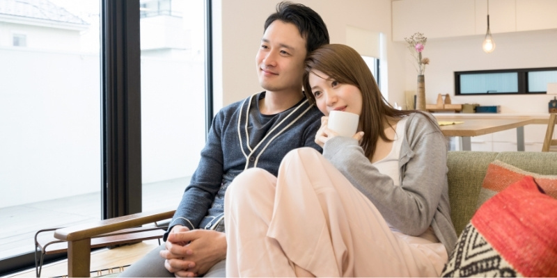 ソファでくっつきながらテレビを見ているカップルの写真