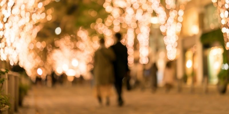 イルミネーションの中を歩くカップルの後姿の写真