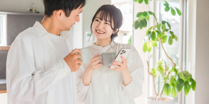 マグカップを片手に微笑むカップルの写真