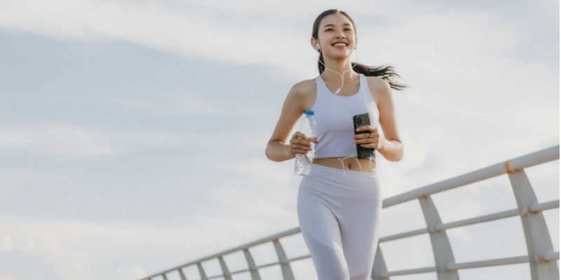 携帯電話を持ちながらジョギングをする女性