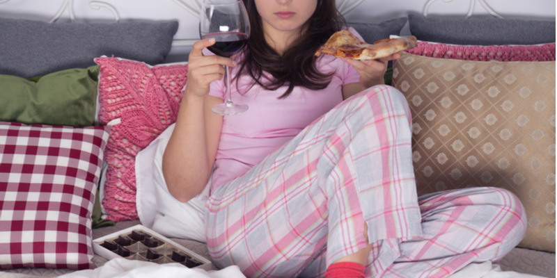 座ってピザを食べながらワインを飲む女性