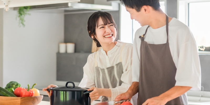 ふたりで楽しそうに料理する男女の写真