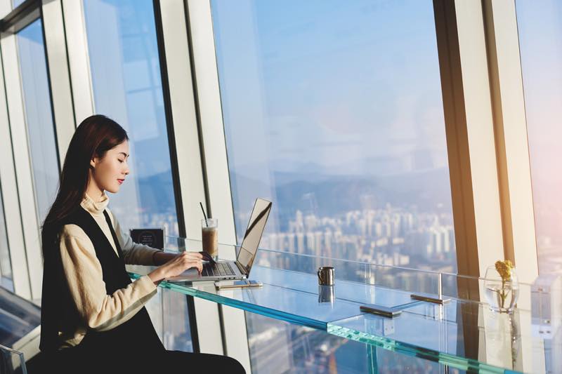 高い場所のカフェの窓際でパソコン作業をする女性