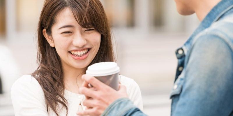 コーヒーを手に持っている男性と笑っている女性