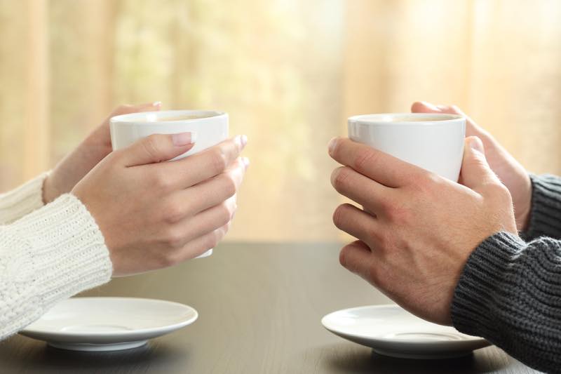 コーヒーカップを持つ男女の手