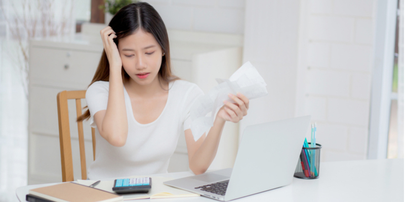 書類を握って頭をかかえる女性