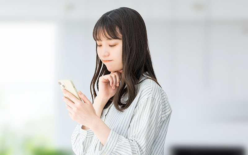 スマホを見て考える女性