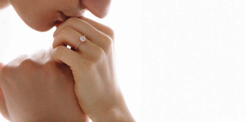 婚約指輪をしている手を唇にあてる女性