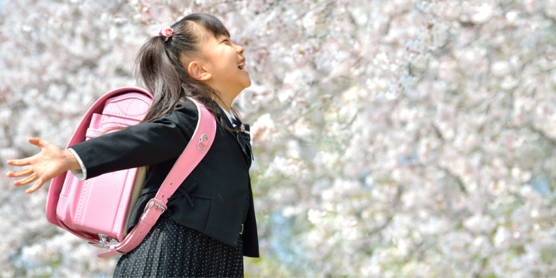 桜の木の下でランドセルを背負ってはしゃぐ女の子