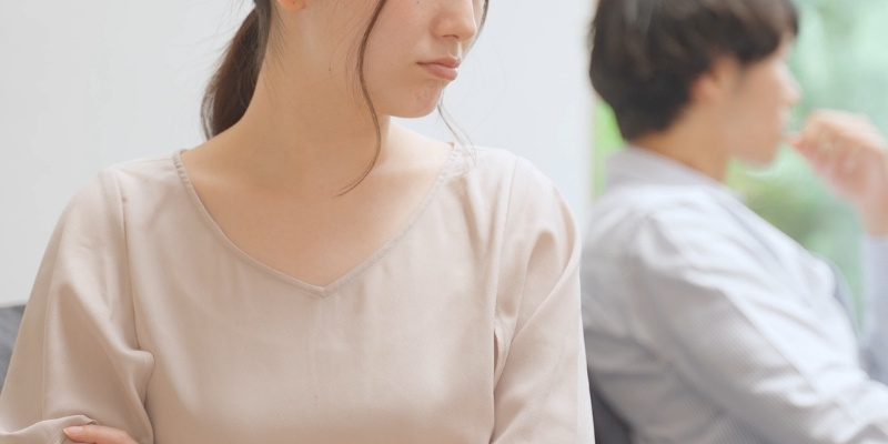 彼氏に背を向けて不機嫌そうに怒る女性の写真