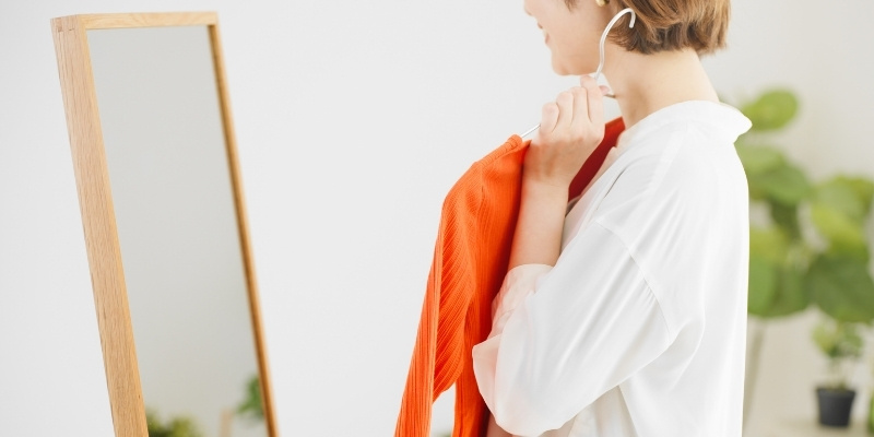 鏡で服選びをする女性の写真