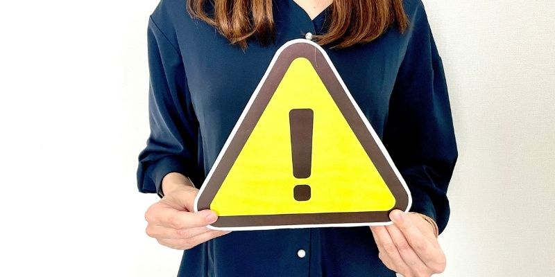 注意マークのパネルを持った女性の写真