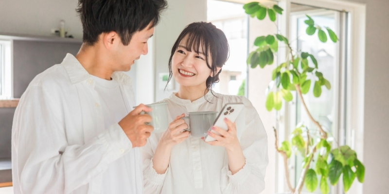スマホをのぞいてほほ笑む夫婦の写真