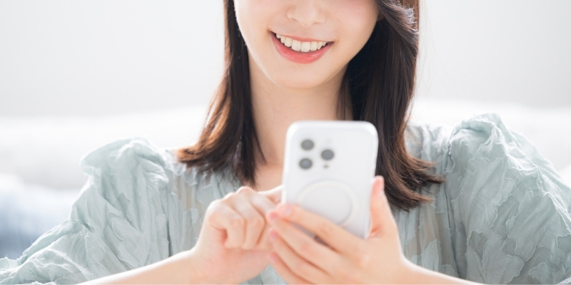 スマホを見てほほ笑む女性の写真