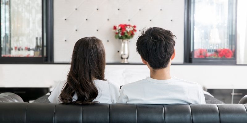 リビングのソファに並んで座ったカップルの後姿の写真