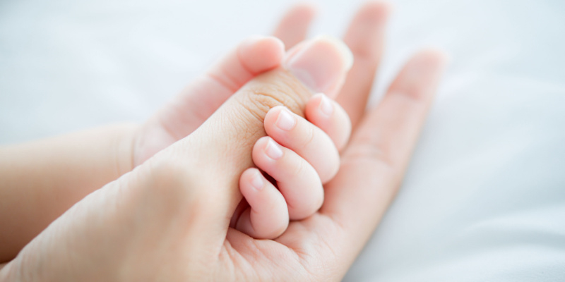 大人の親指を握る赤ちゃんの手