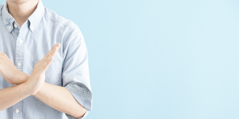 バツマークを作る男性の写真