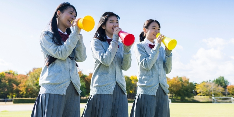 メガホンを持って応援している女子高生３人の写真