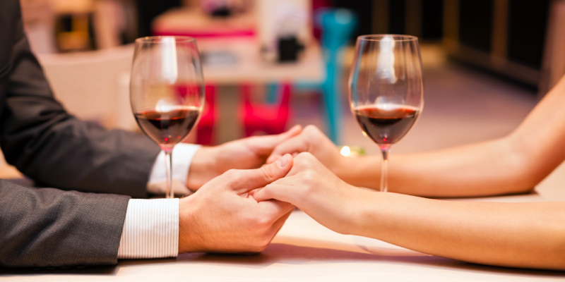ワインを置いたテーブルの上で手を取り合う男女